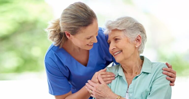Caregiver standing with resident outside in sunshine